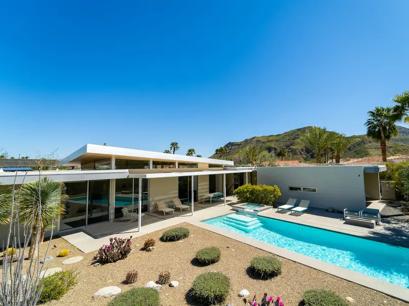 Backyard pool in a desert garden, with palms and dry mountains behind