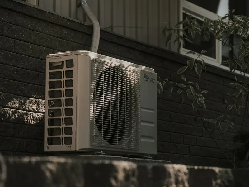 Outdoor air conditioning unit against a brick house wall