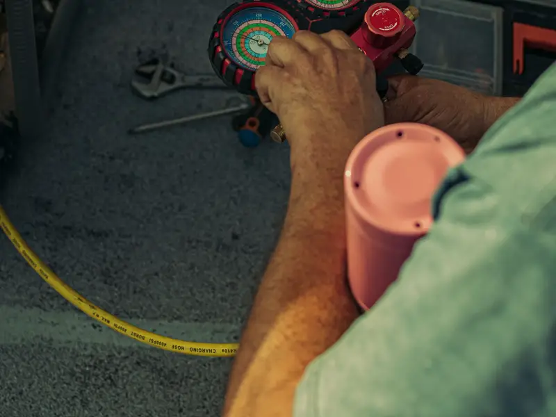 Hands adjusting a refrigerant pressure gauge during an AC check